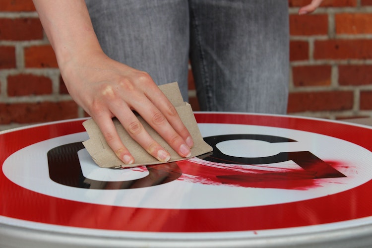 Ein Stück Pappe dient als Spachtel, um damit die gesprayte Farbe zu verteilen. Foto: Heinzel