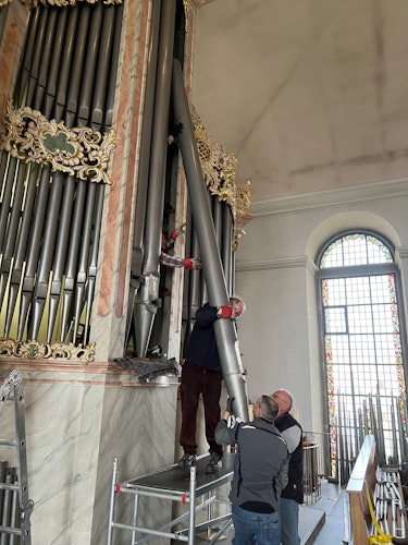 Mit vereinten Kräften: Die Orgelbauer entnehmen die 5 Meter hohe und circa 100 Kilogramm schwere Pfeife, um sie zu reinigen und wieder in Form zu bringen. Foto: Strauch