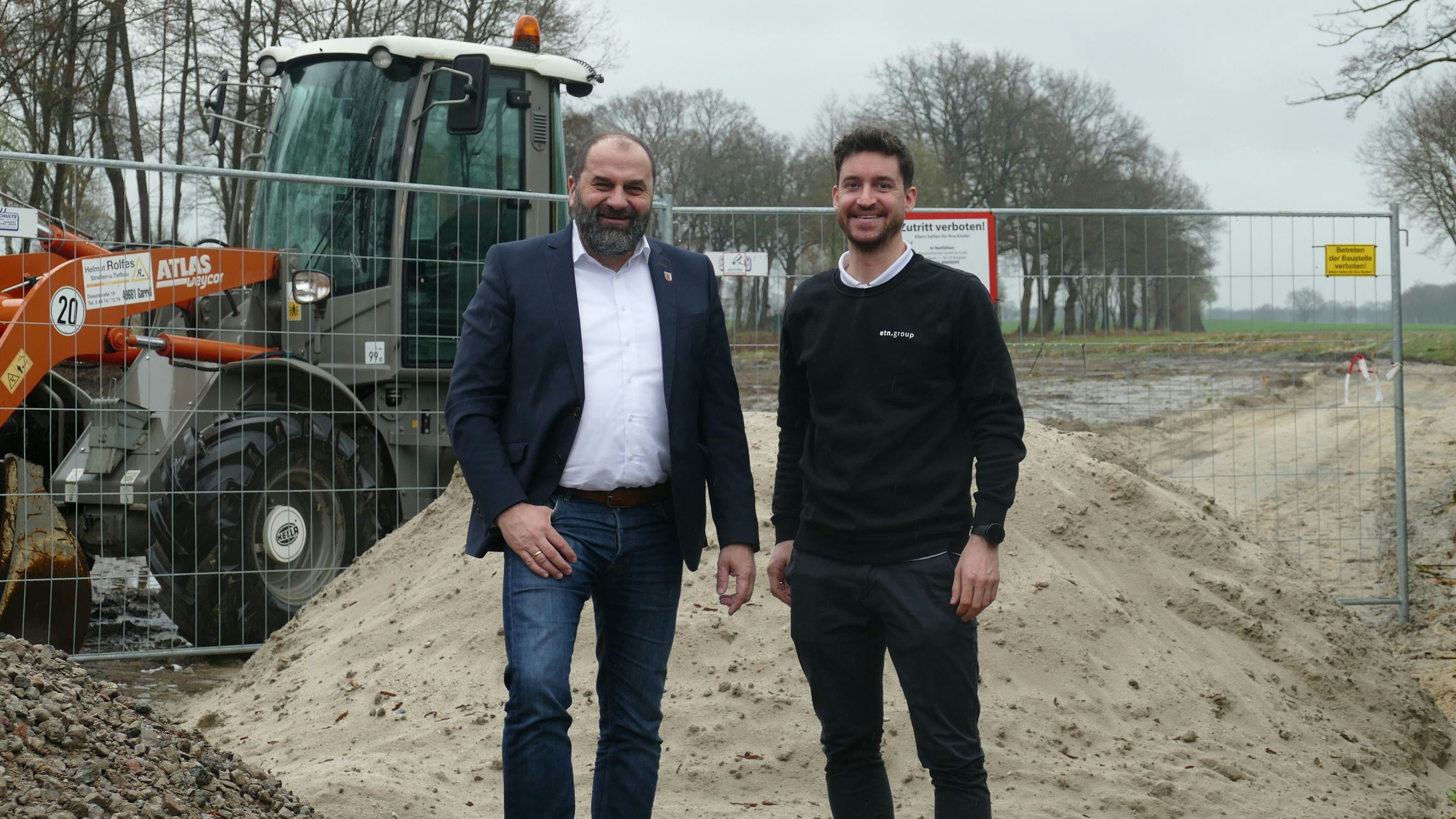 Baubeginn: Bürgermeister Sven Stratmann (links) und Henning Harlacher von der ETN Group am Zaun der Baustelle in Pirgo. Hier entsteht derzeit das Fundament für den ersten Friesoyther Richtfunkmast. Foto: Stix