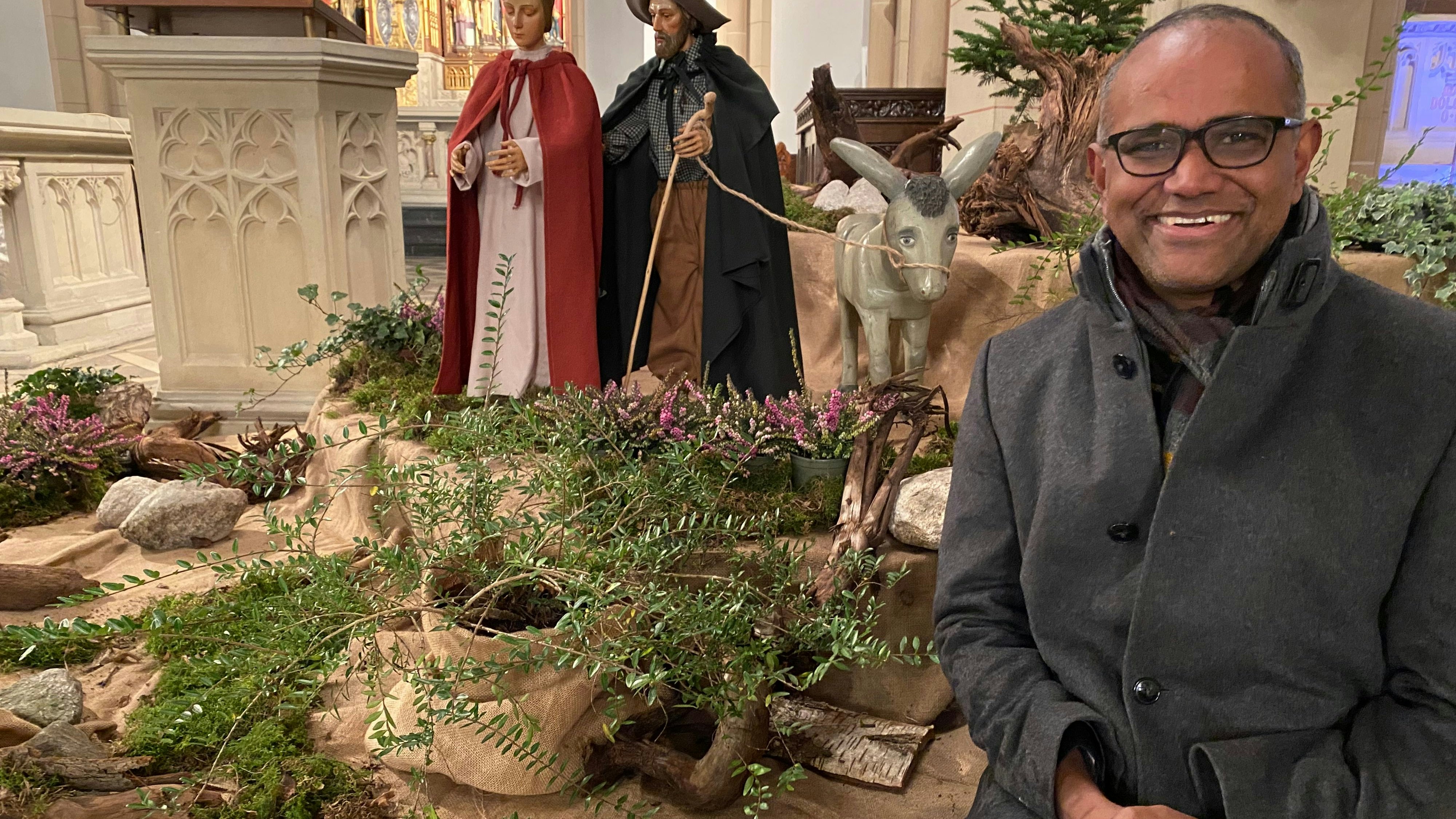 Vor der Friesoyther Krippe im Aufbau: Pfarrer Aby stammt aus Indien und berichtet, wie in seiner Heimat Weihnachten gefeiert wird. Foto: Wimberg