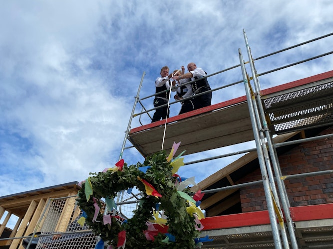 Teamarbeit: Andreas Lichtner, Ralf Dwenger und Eduard Lichtner ziehen die von Caritas-Mitarbeitern gebundene Krone aufs Dach. Foto: Wimberg