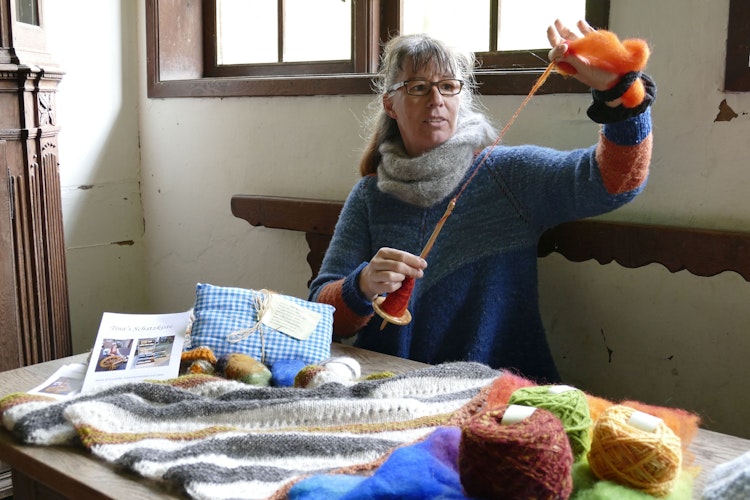 Lebendiges Handwerk im Museumsdorf: Wolle spinnen mit einer Handspindel, anschaulich vorgeführt. Foto: Museumsdorf