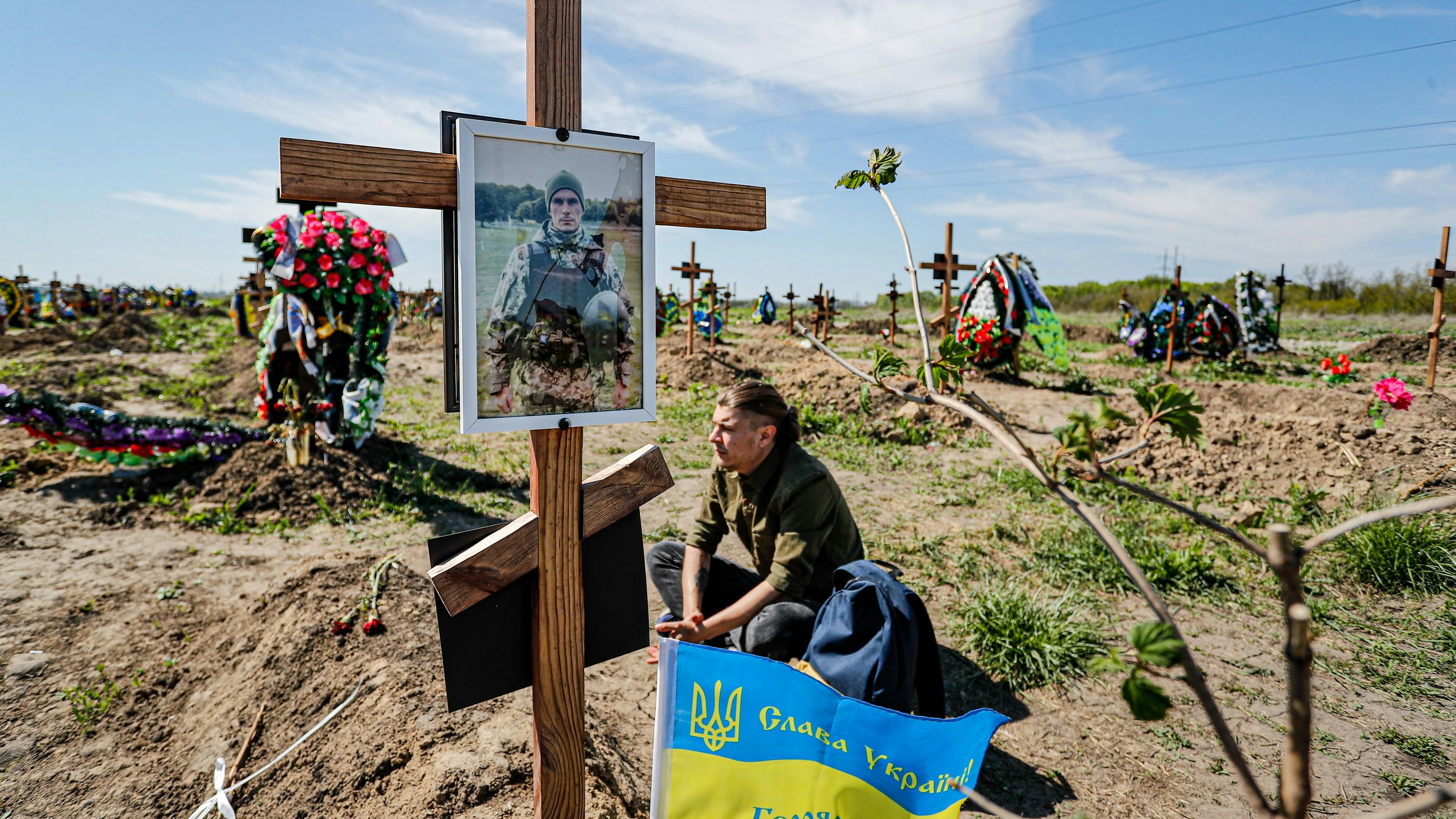 Der Ukrainer Alexander sitzt in Dnipro vor dem Grab seines älteren Bruders und Soldaten Evgeny Ketov, der im März während der russischen Invasion in der Region Donezk im Donbass ums Leben gekommen ist. Foto: dpa/Shou-Yi