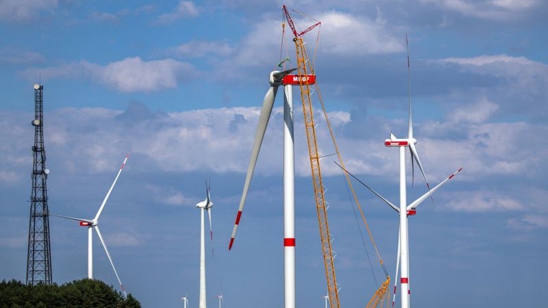 Ein Kran hebt auf der Baustelle eines neuen Windparks in Mecklenburg-Vorpommern ein Rotorblatt für die Montage an das Generatorhaus. Foto: dpa/Büttner