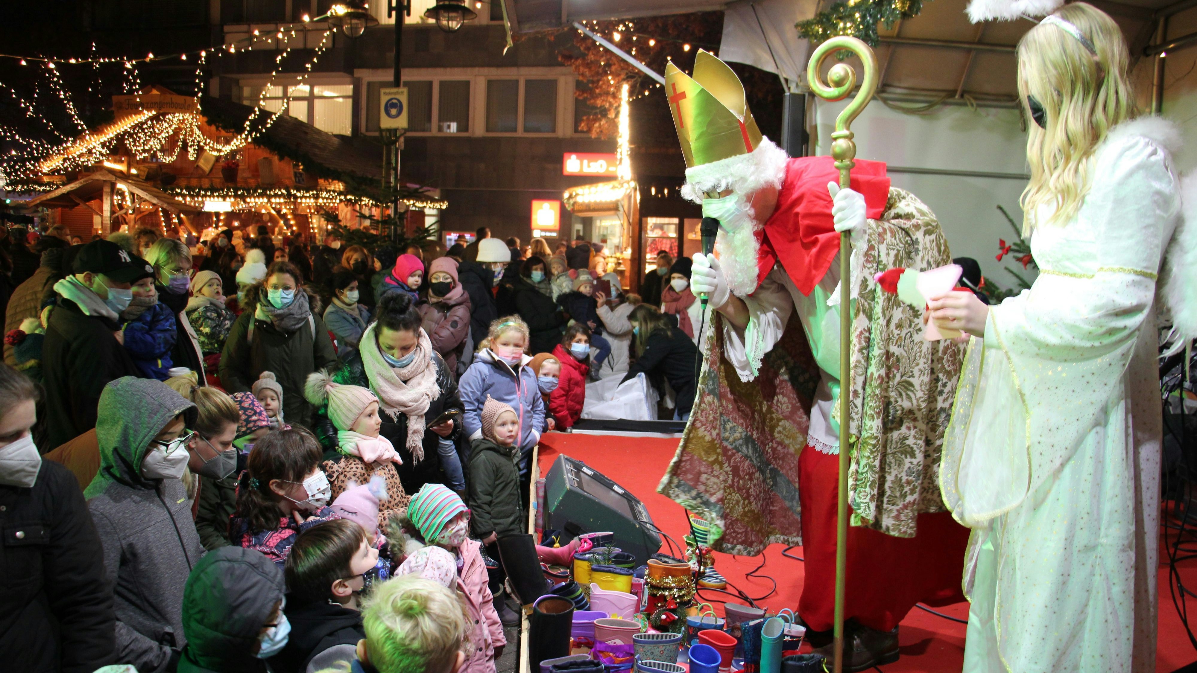 Erwartungsvolle Gesichter auf dem Alten Markt in Vechta: Der Nikolaus und ein Engel sprachen zur Markteröffnung zu den Besuchern. Die Kinder konnten wieder ihre Stiefel abgeben. Foto: Speckmann